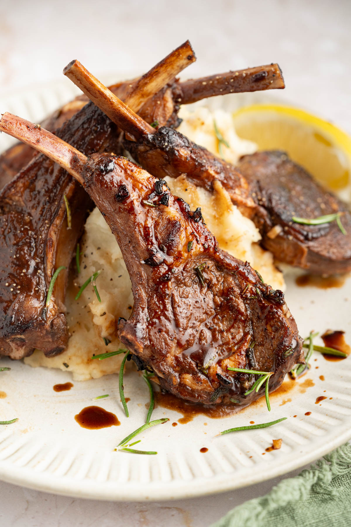 Three baked lamb chops on a plate with mashed potatoes.