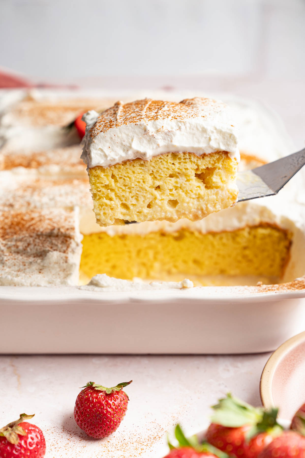 A serving spatula removes a piece of tres leches from the pan.