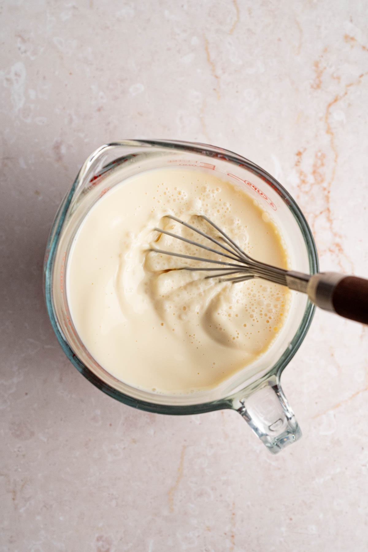 The milk mixture in a large bowl with a whisk after whisking together.