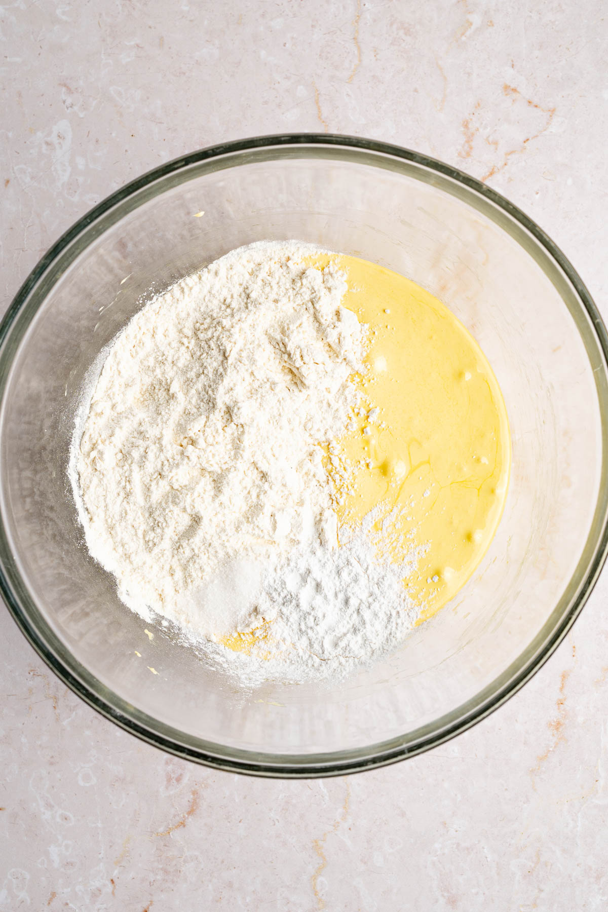 The beaten egg yolk mixture in a large glass bowl with the flour, salt, and baking powder.