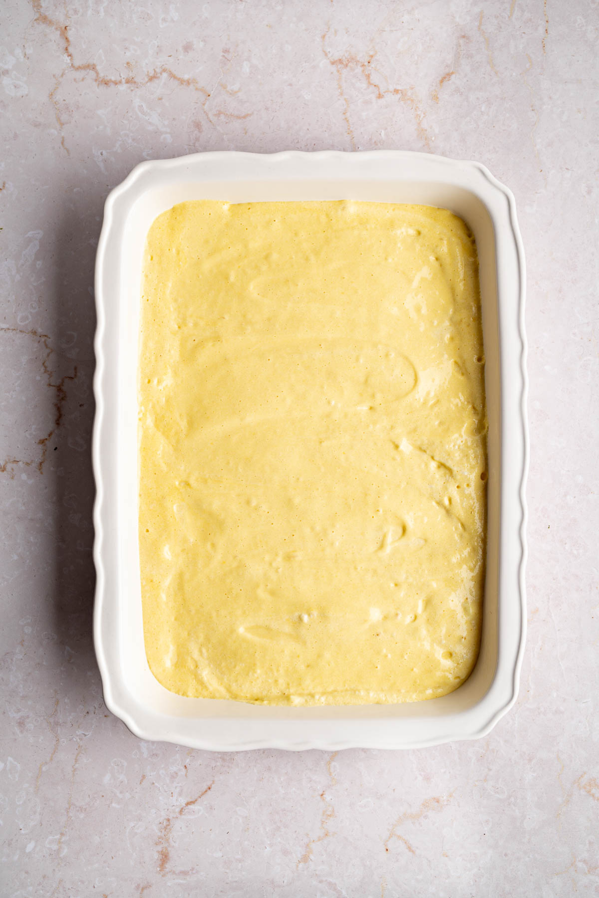 The cake batter poured into the baking dish before baking.