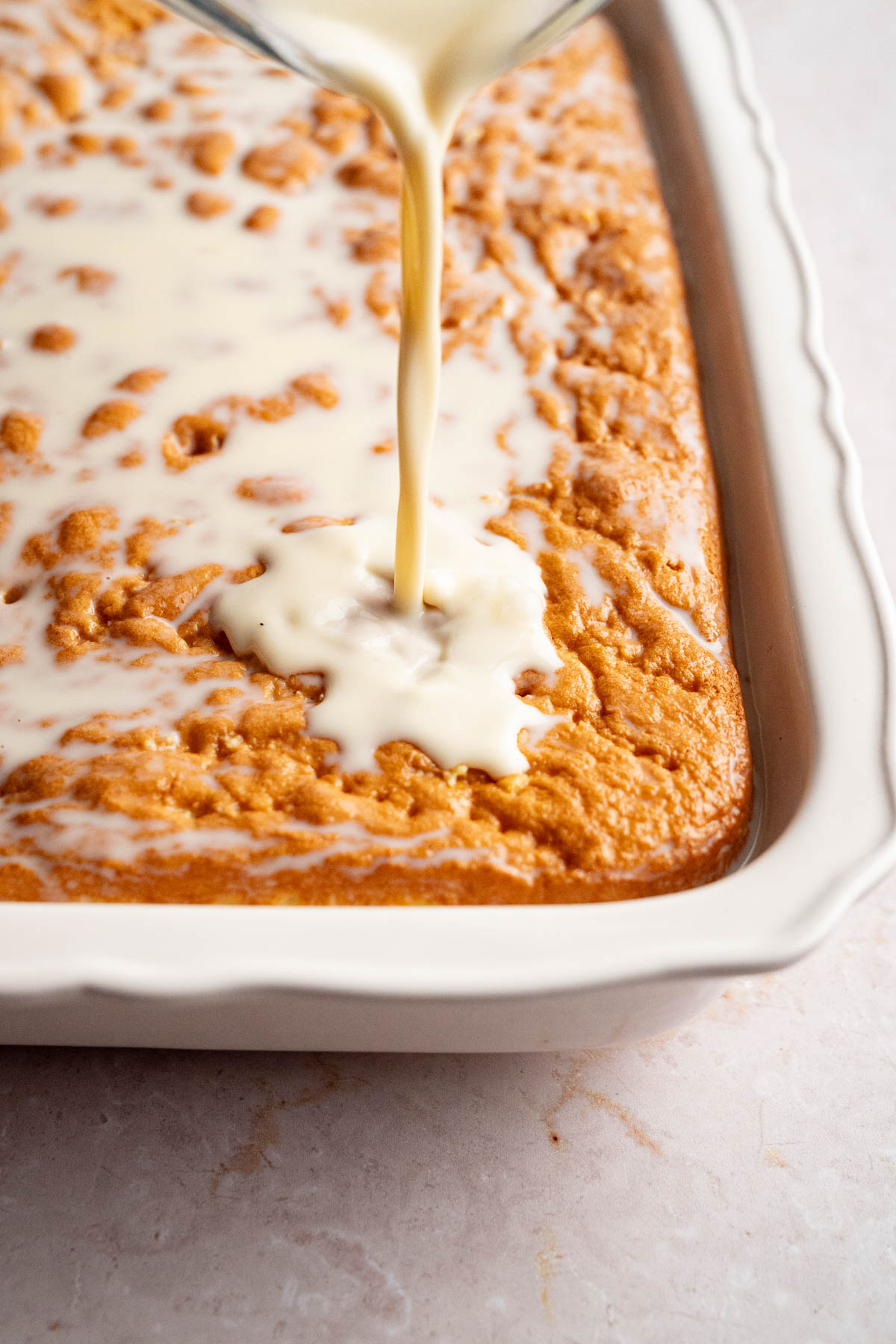 The milk mixture being poured over the cake.