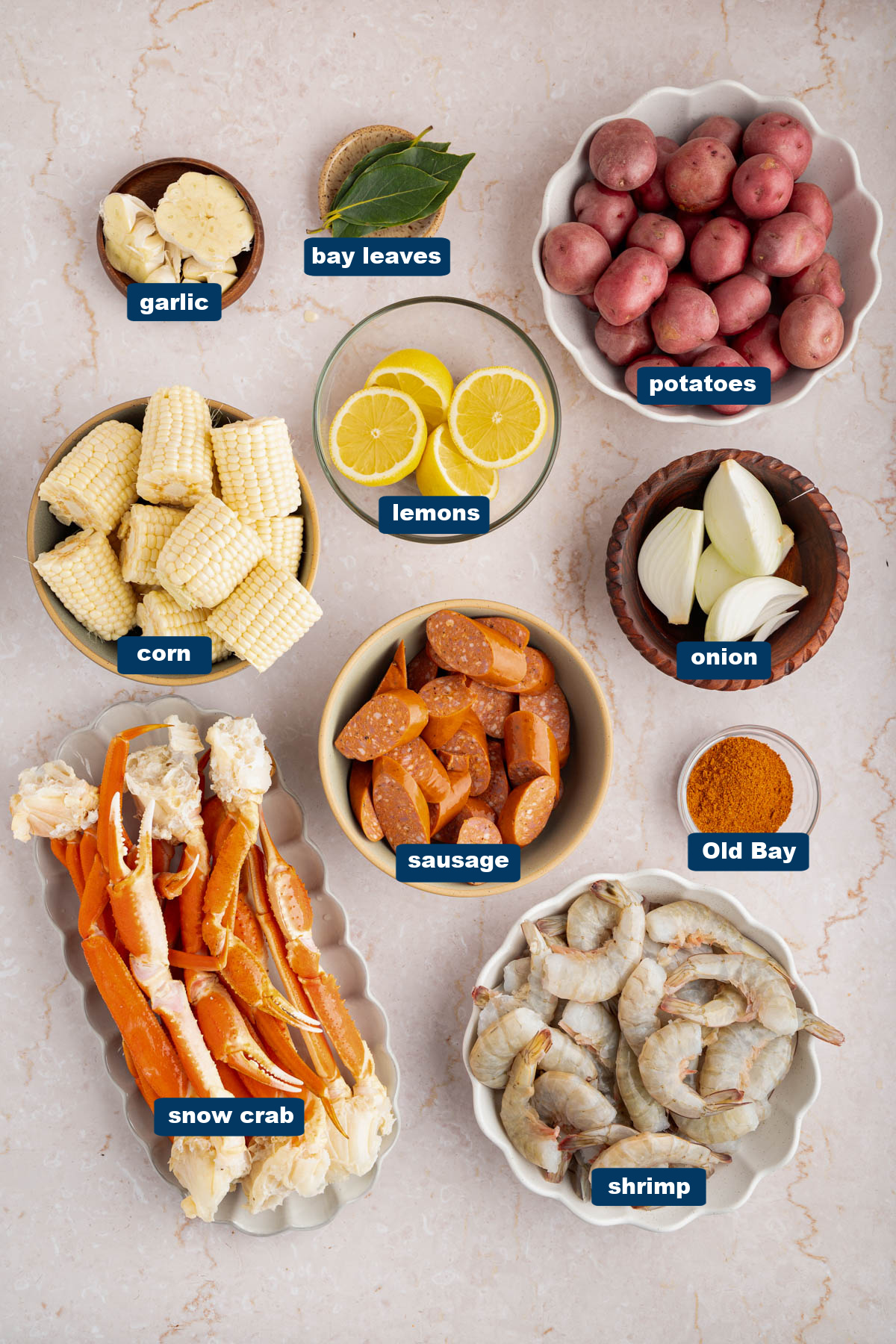 Some of the ingredients for seafood boil in bowls on a countertop.