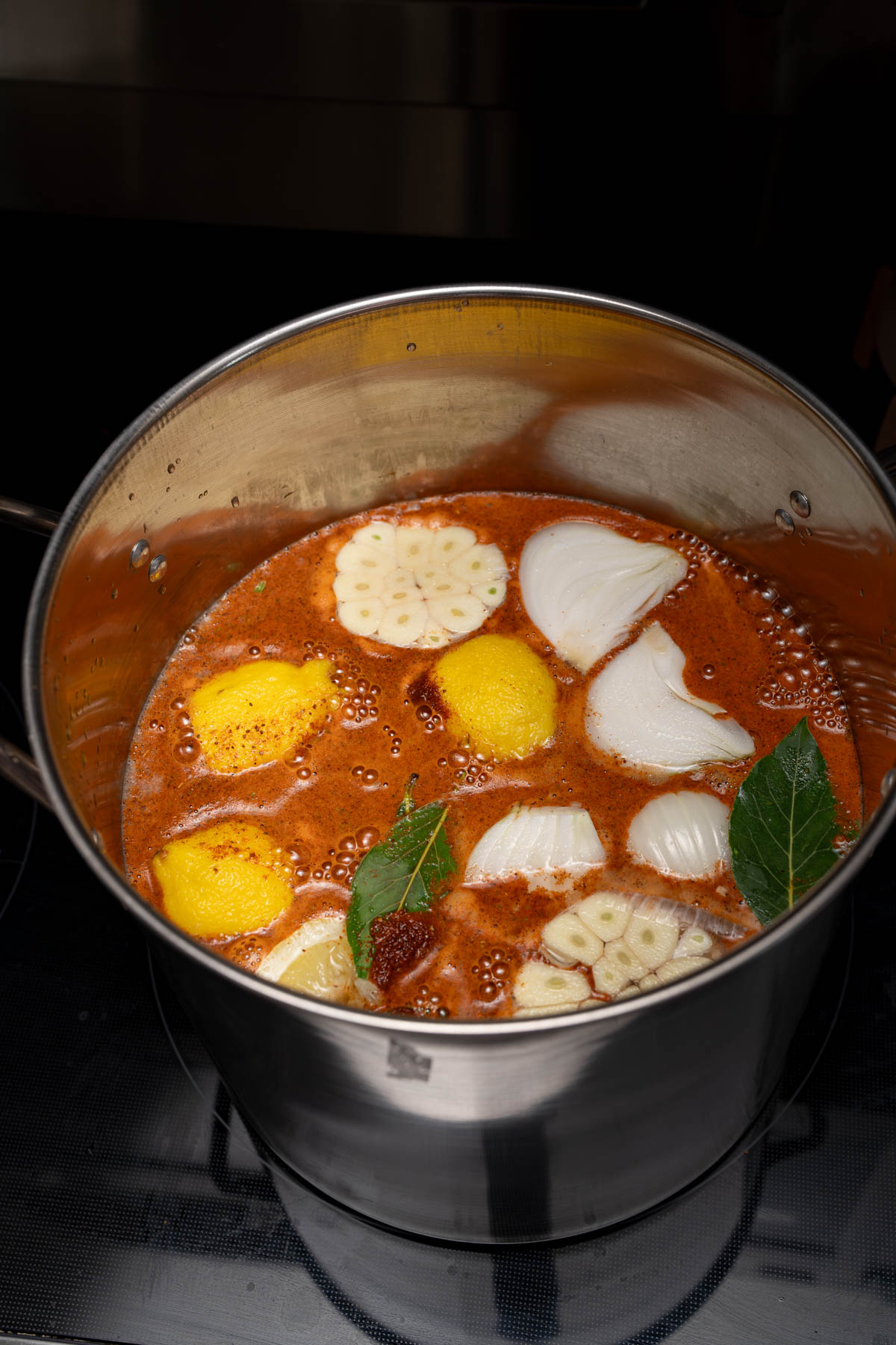 The Old Bay, lemons, garlic, onion, and bay leaves in a large stockpot before boiling.