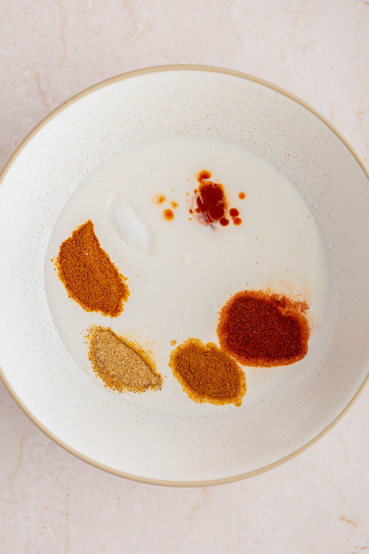 The ingredients for the buttermilk coating in a large white bowl on a countertop.