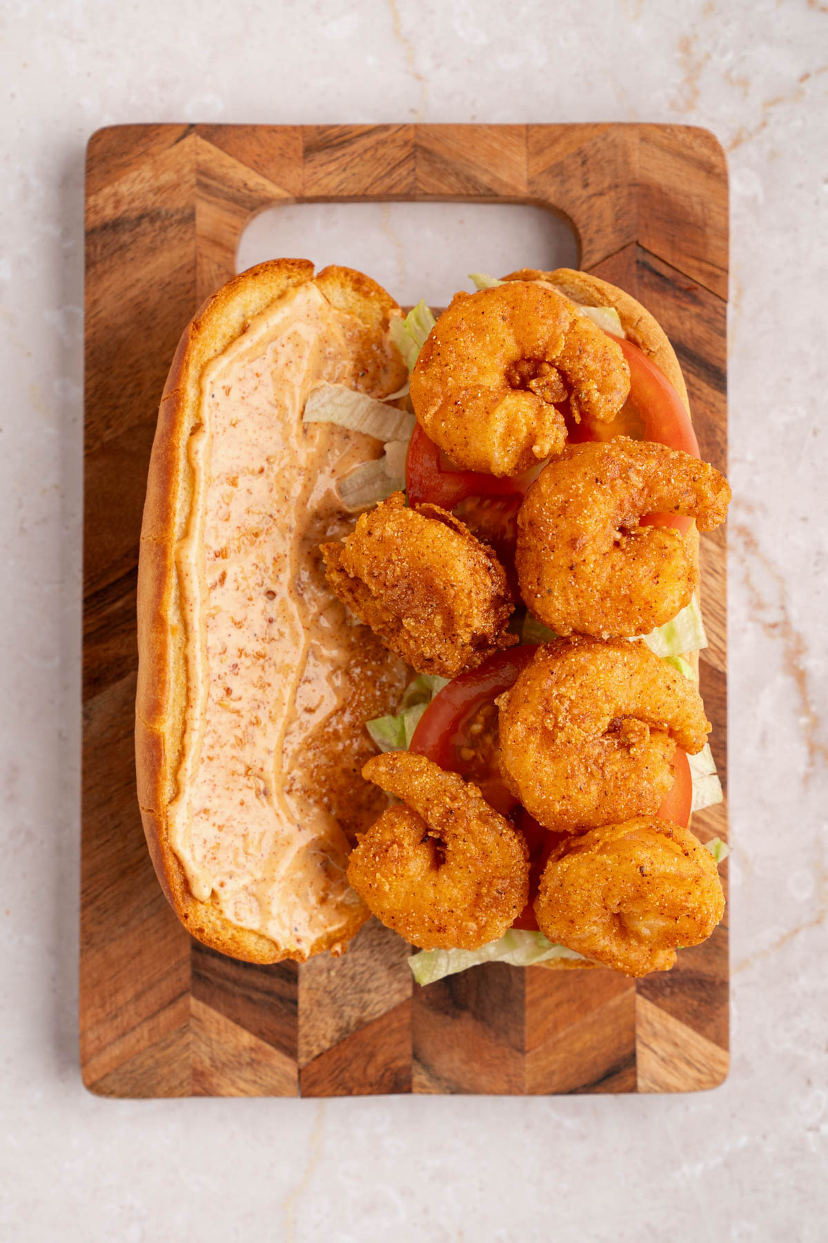 The lettuce, tomato, and fried shrimp layered on a french roll that is spread with the remoulade sauce.