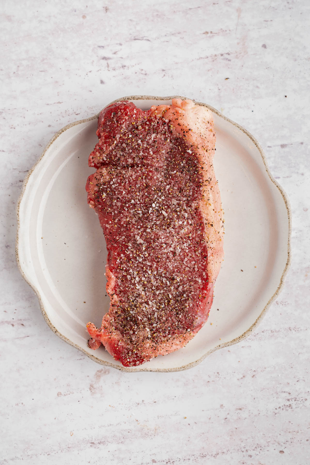The steak with salt and pepper on it before searing.