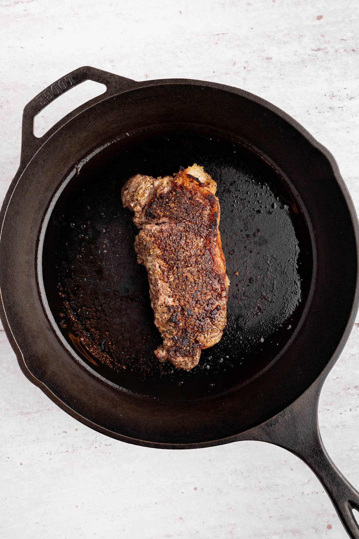 The seared steak in a cast iron skillet.