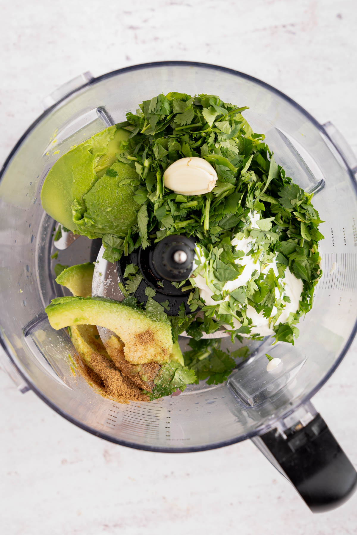 All of the ingredients for the avocado-lime crema in the food processor bowl before blending.