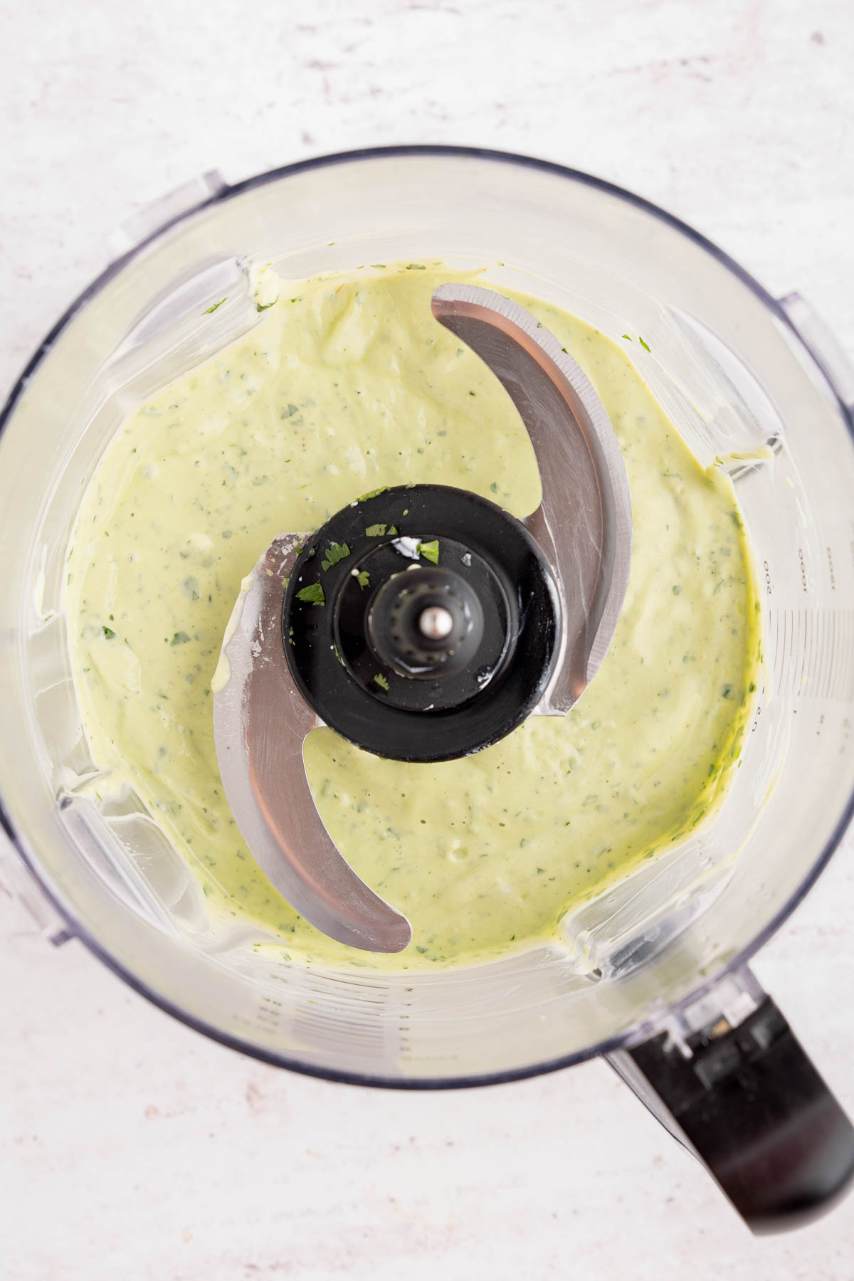 The avocado-lime cilantro crema in the food processor bowl after blending.