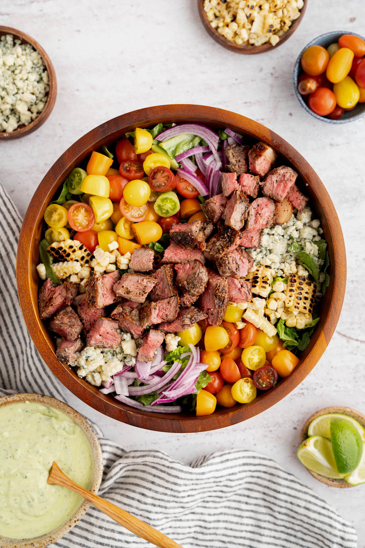 The finished steak salad in a bowl with the avocado lime crema off to the side.