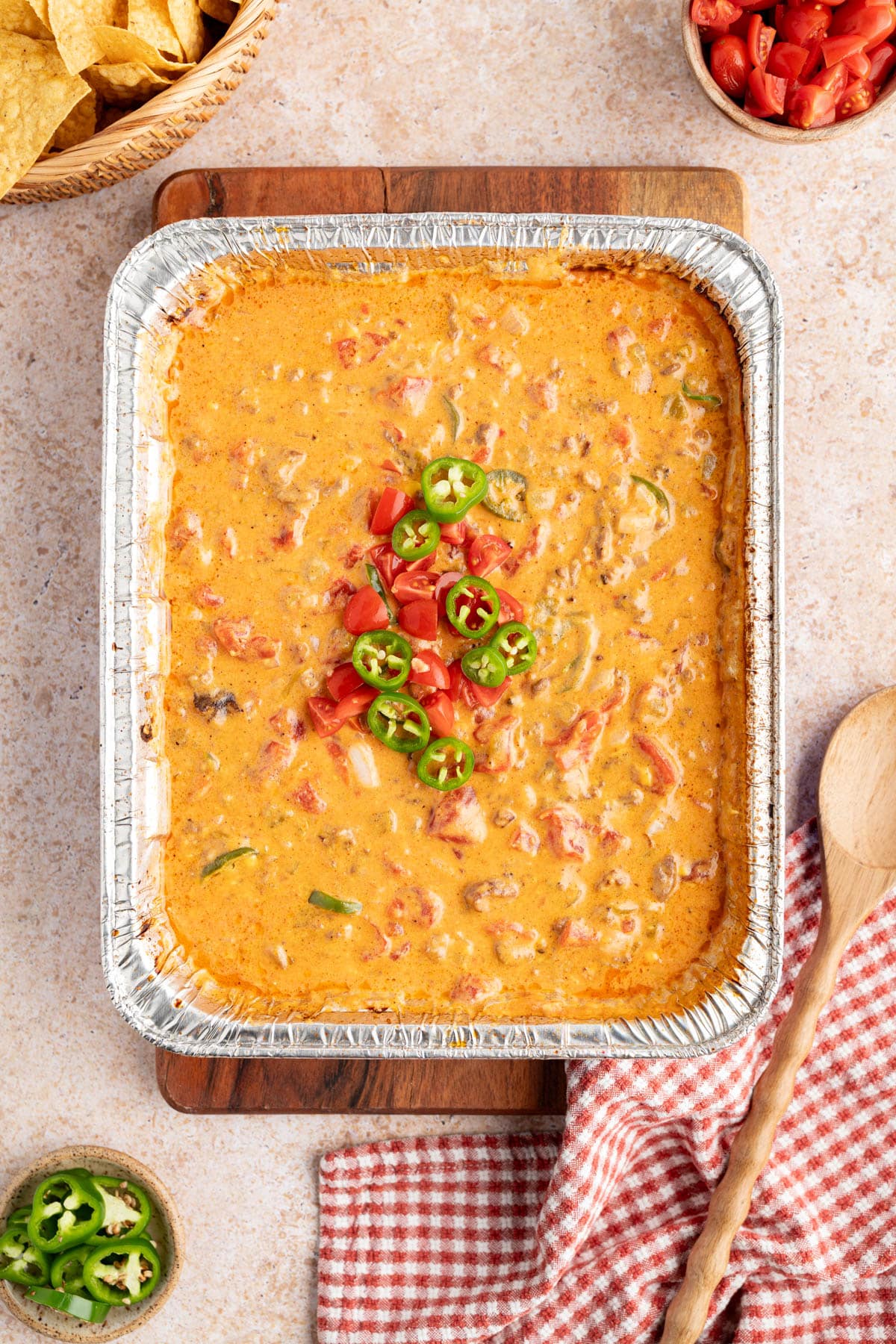 The grilled rotel dip in a baking pan on a wooden cutting board for serving.