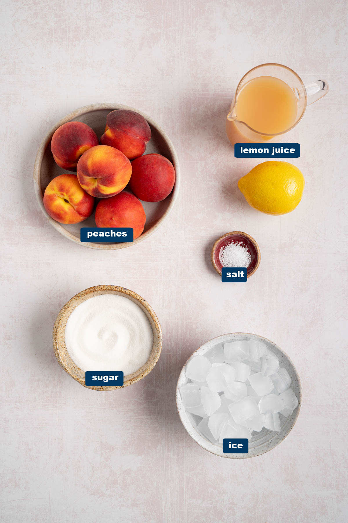 All of the ingredients for peach lemonade in bowls on a white countertop.