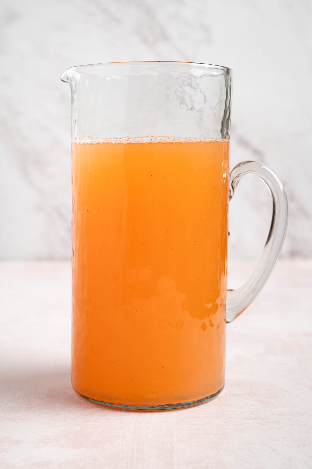 The peach syrup with the lemon juice and cold water in a pitcher.