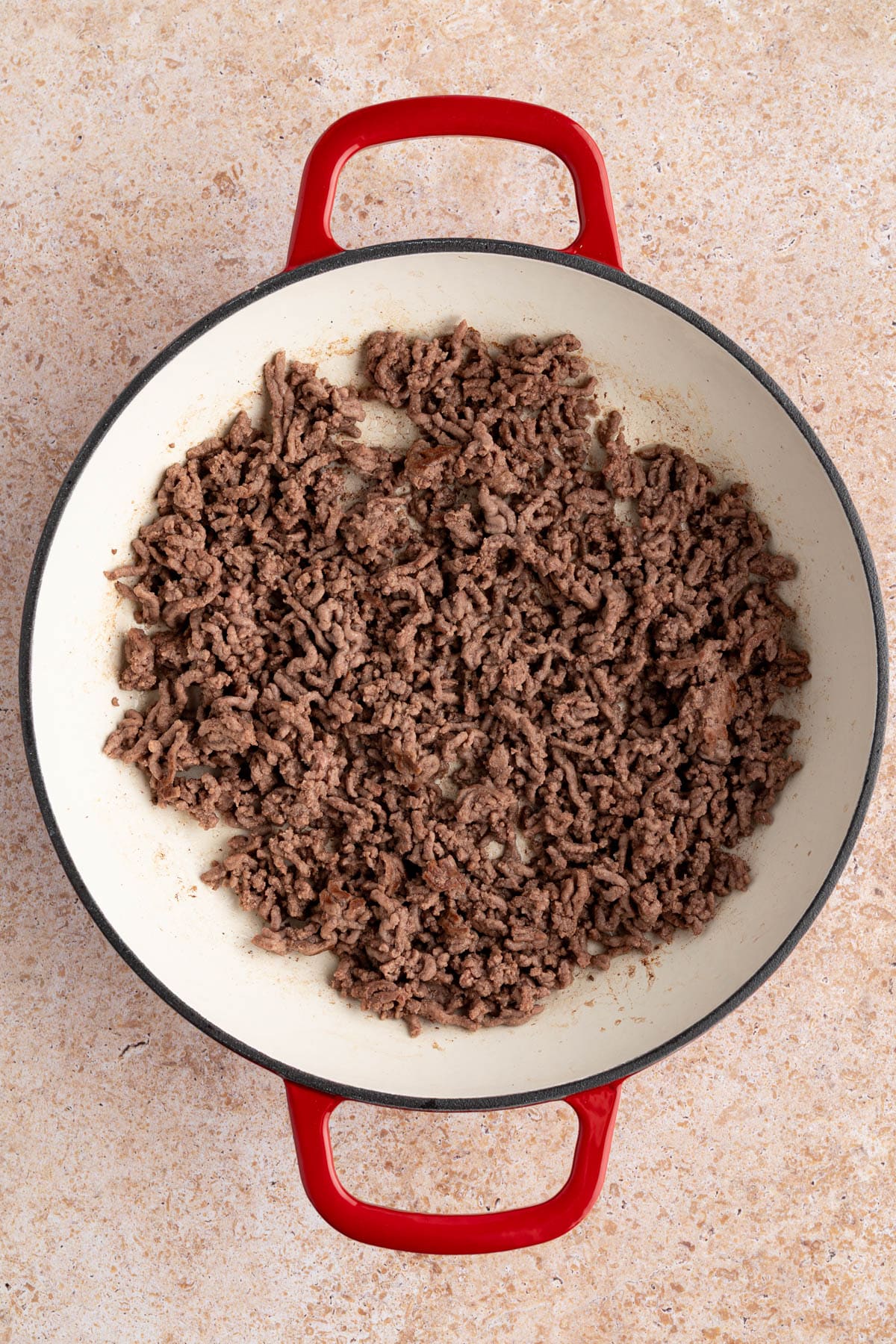 The cooked ground beef in the skillet before adding the seasonings.