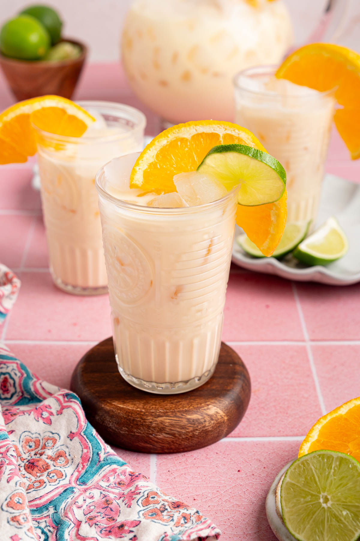 Three glasses of morir sonando on a countertop with a pitcher for serving.