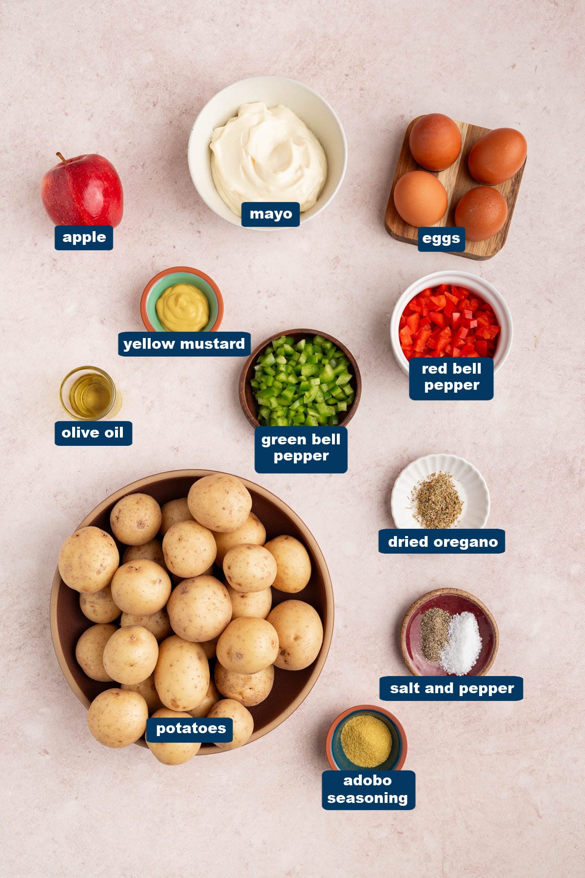 All of the ingredients for puerto rican potato salad in bowls on a countertop.