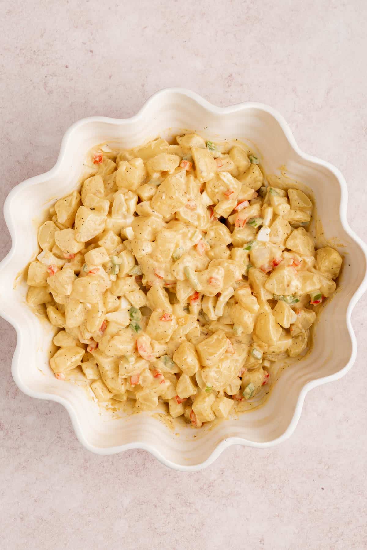 The potato salad mixed together in a white bowl.