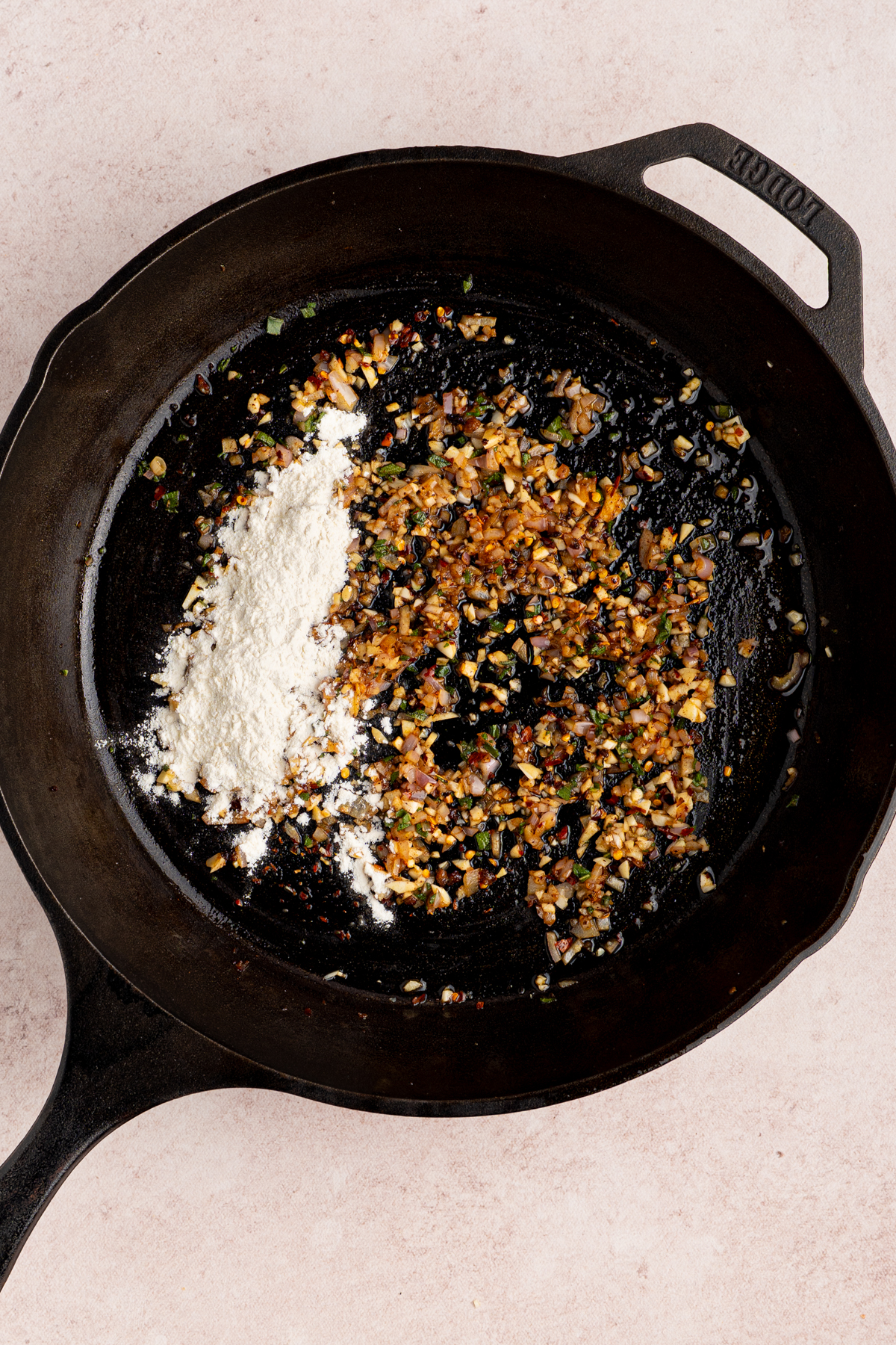 The flour in the cast iron pan with the cooked aromatics.