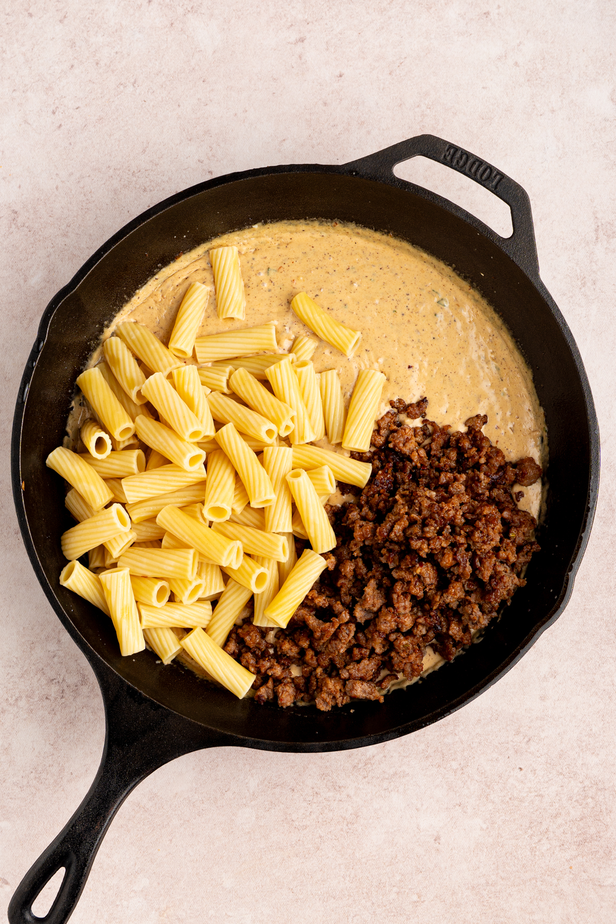 The cooked pasta and cooked sausage in the pan before mixing together.