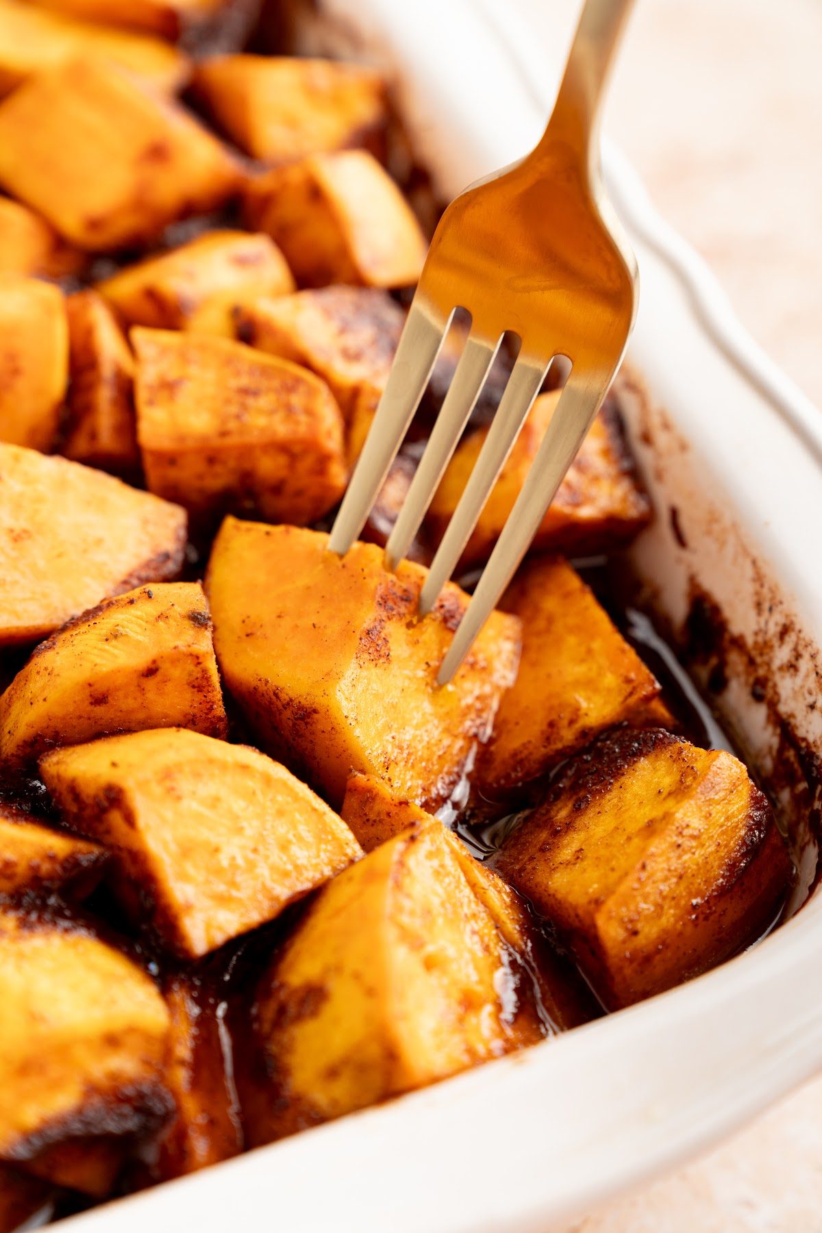 A fork sliding easily into a baked yam piece that is soft but still holding its shape