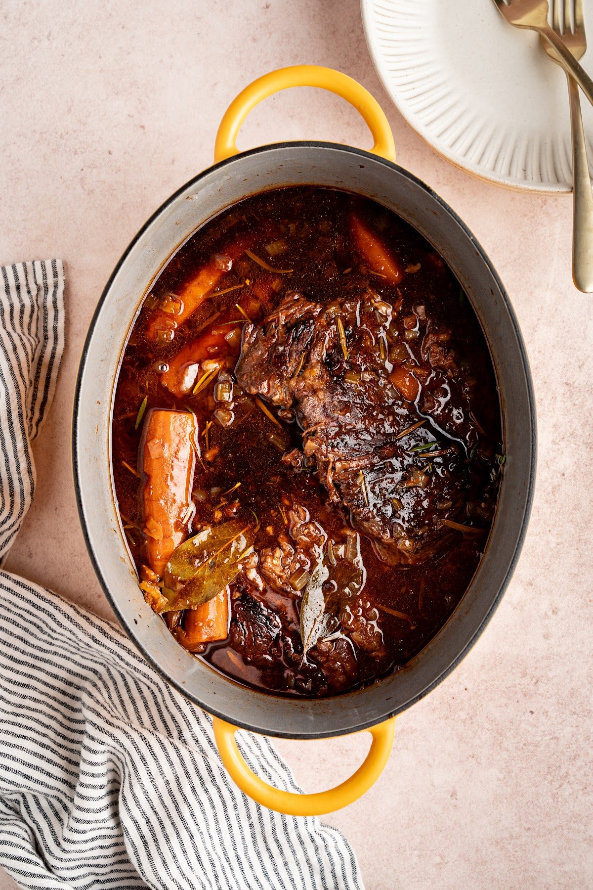 Red wine braised pot roast in a Dutch oven after two and a half hours, with tender whole carrots and a dark glossy sauce