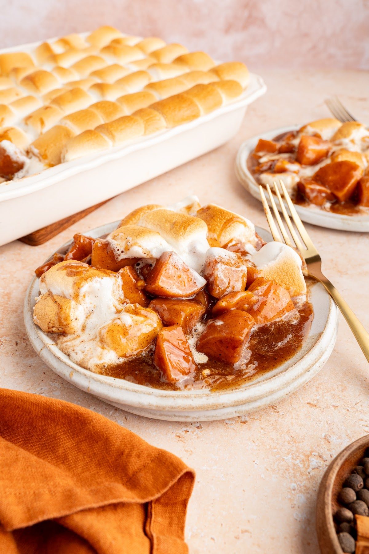 Candied yams with marshmallows served in a small bowl with the baking dish behind