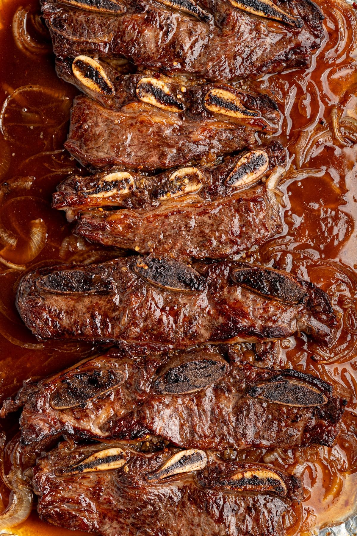 Sheet pan Korean short ribs after broiling, with dark caramelized edges and a lacquered glaze
