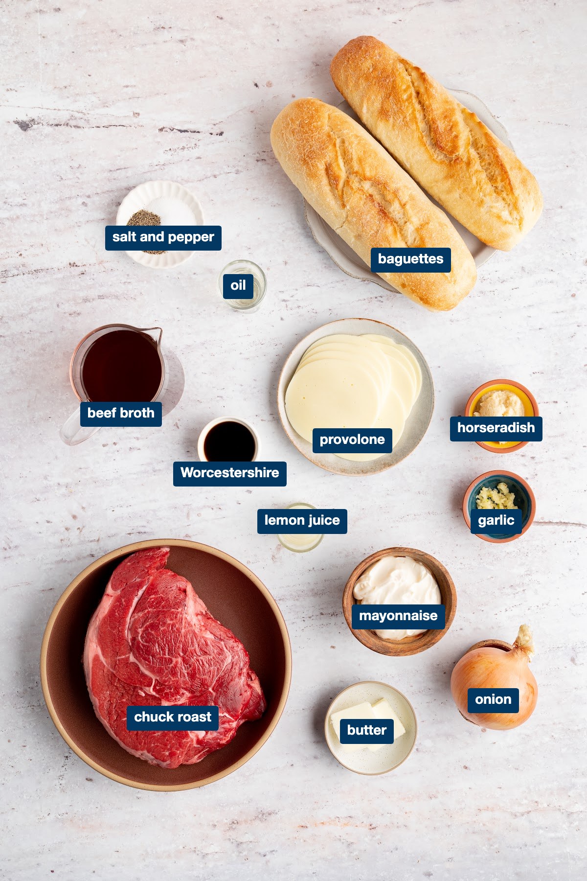 Labeled ingredients for French dip sandwiches: chuck roast, baguettes, provolone, beef broth, Worcestershire sauce, onion, butter, mayonnaise, horseradish, garlic and lemon juice