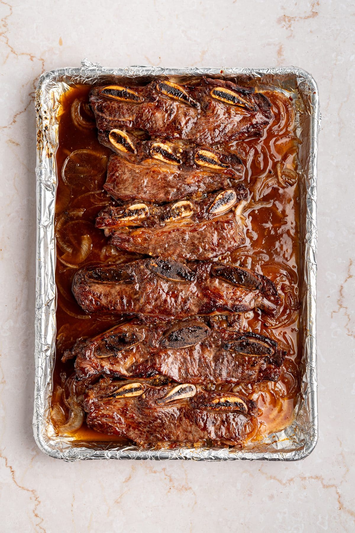 Short ribs after roasting, with the onions collapsed into the sauce around them