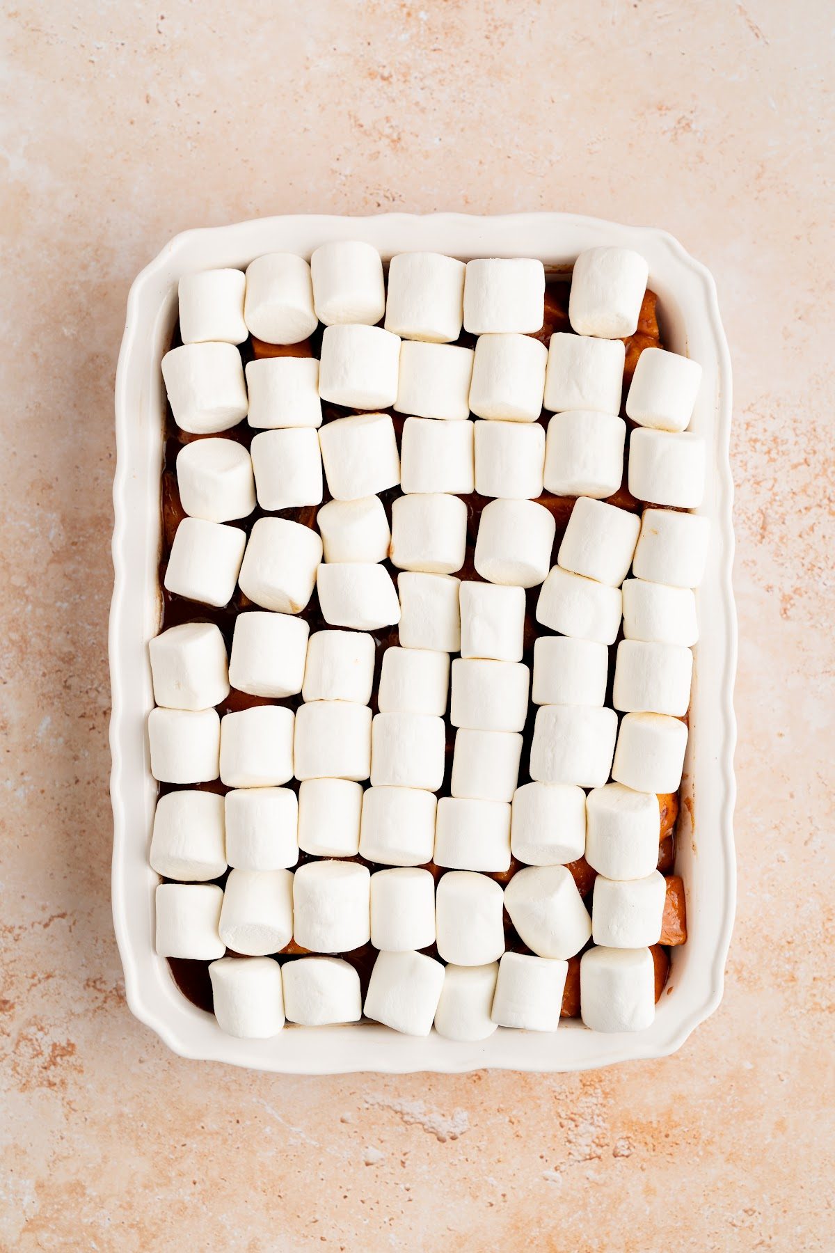 An even layer of regular size marshmallows laid across the baked candied yams before toasting