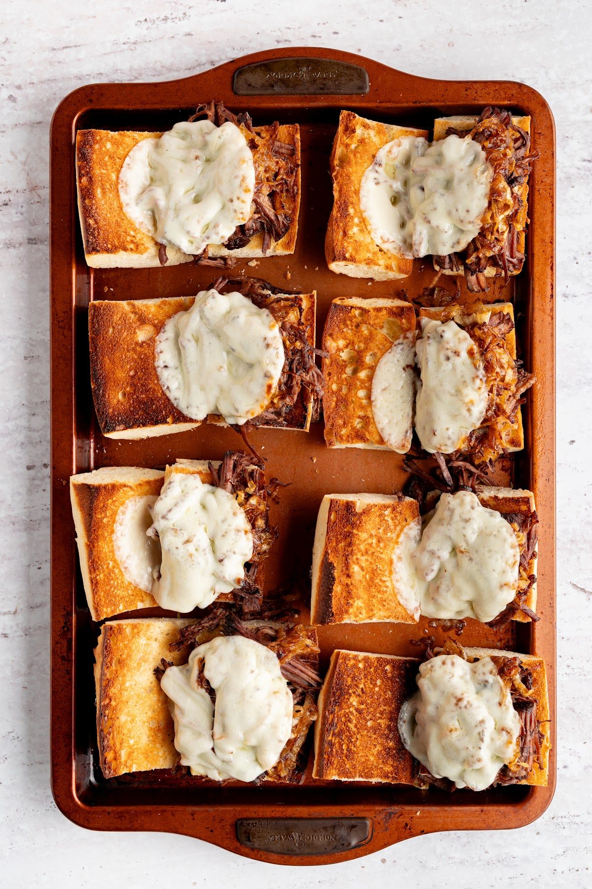 Slices of provolone laid over the shredded beef and onions before broiling
