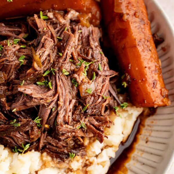 Red wine braised pot roast shredded over creamy mashed potatoes with whole braised carrots and gravy spooned over the top