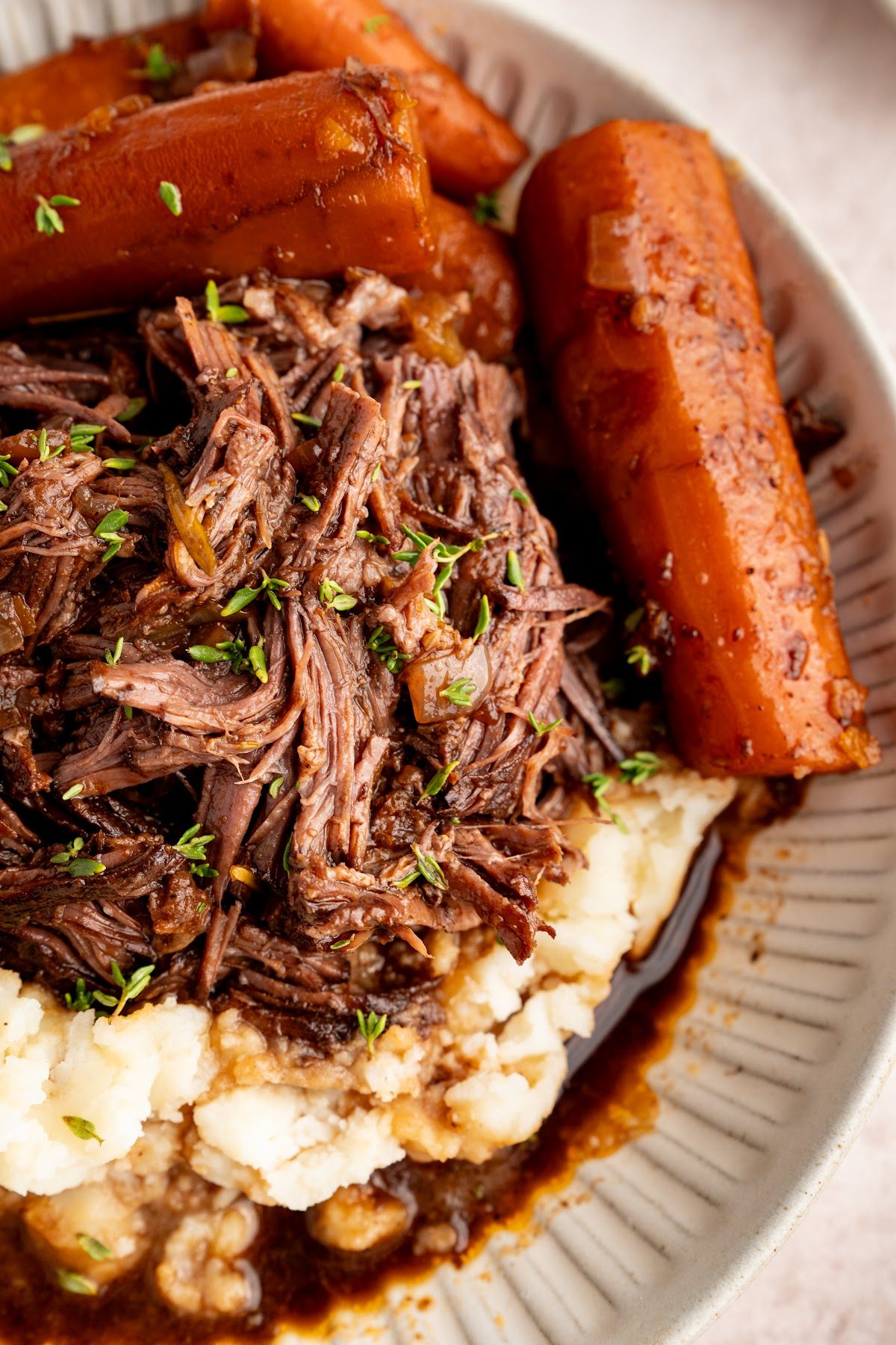 Red wine braised pot roast shredded over creamy mashed potatoes with whole braised carrots and gravy spooned over the top
