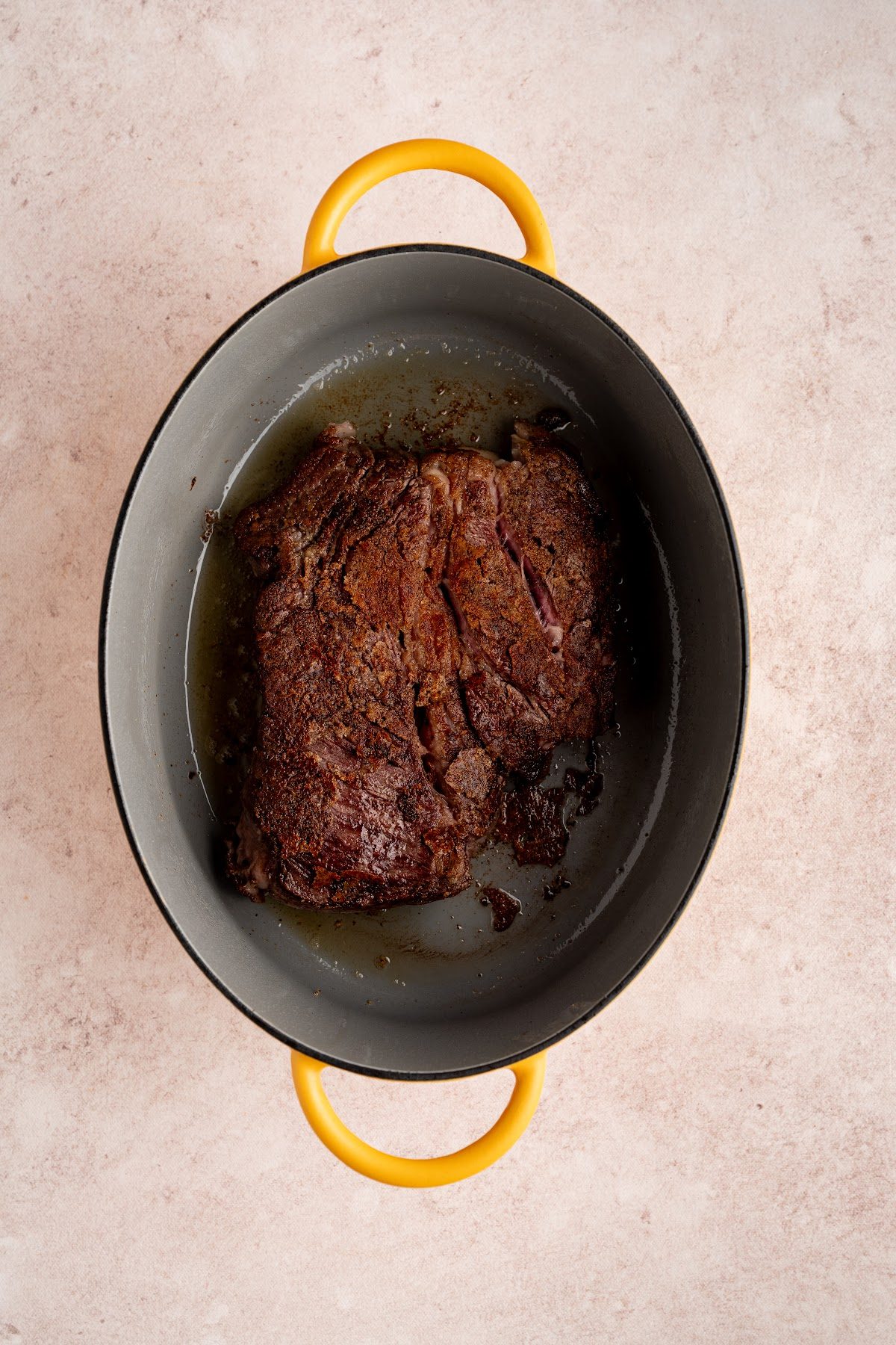 A chuck roast seared deep brown on all sides in a Dutch oven