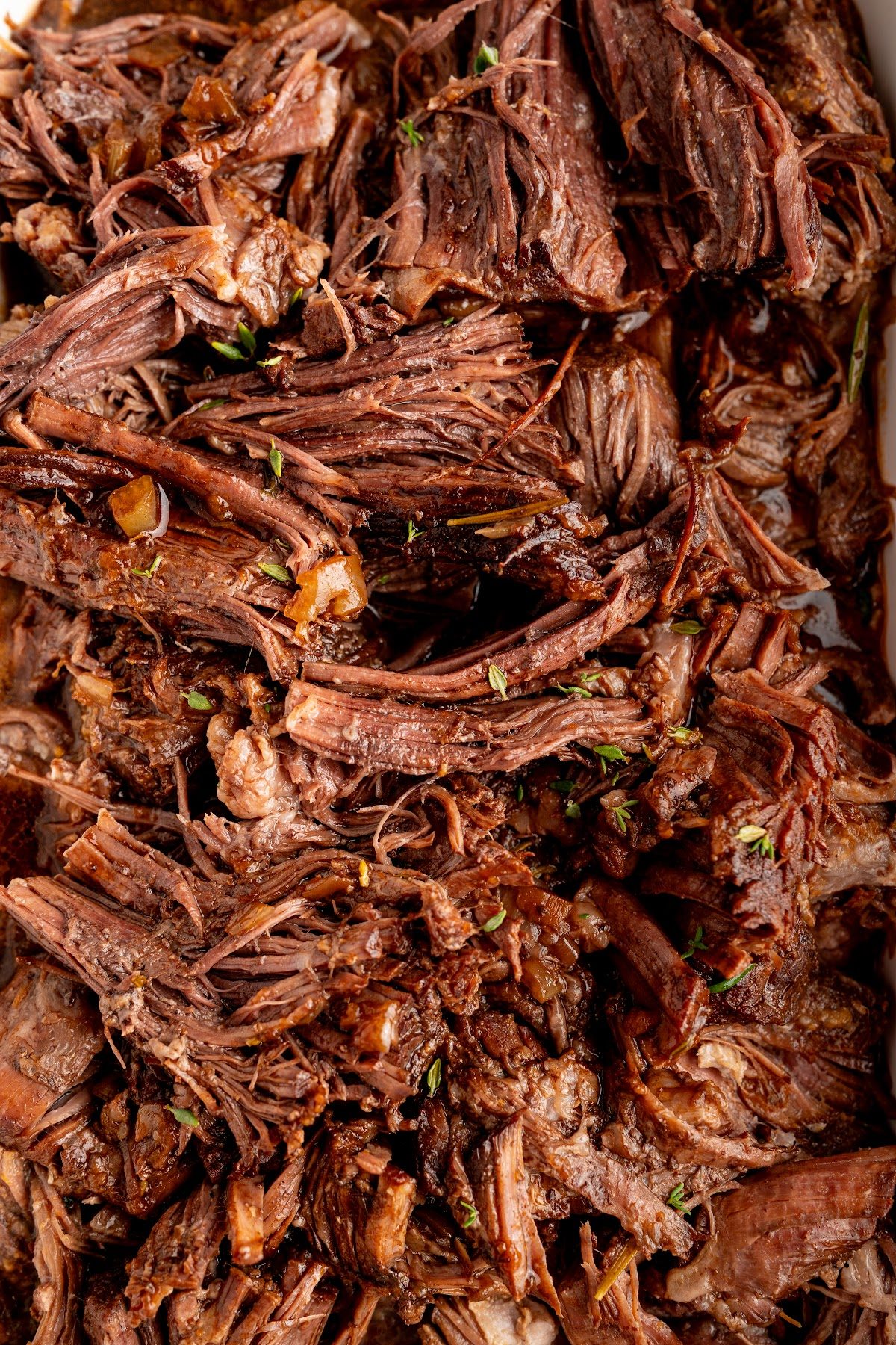 Close-up of shredded red wine braised pot roast coated in dark braising sauce